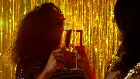 Cerca-De-Dos-Mujeres-Bailando-En-Un-Bar-O-Discoteca-Bebiendo-Alcohol-Con-Confeti-Dorado-Cayendo